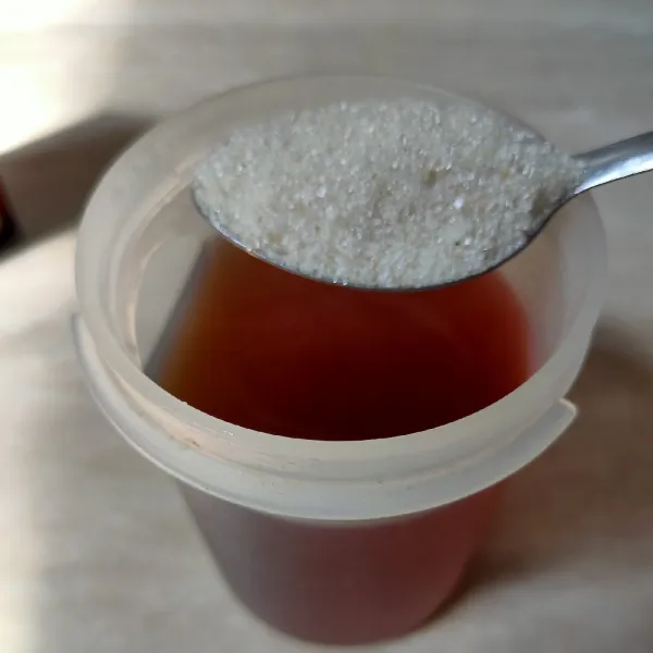 Tambahkan gula pasir ke dalam teh jahe, aduk rata.