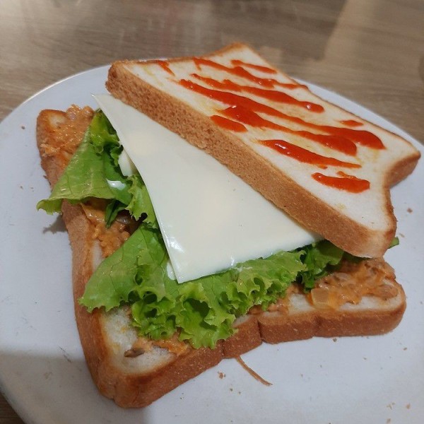 Siapkan isian sandwich. Oleskan tuna pada satu sisi roti, tambahkan selada yang sudah dicuci dan dipotong, tambah keju. Beri tambahan saus dan mayonais sesuai selera.