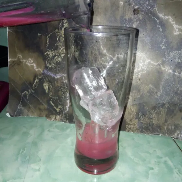 Siapkan gelas saji, tambahkan es batu dan strawberry yang telah diblender.