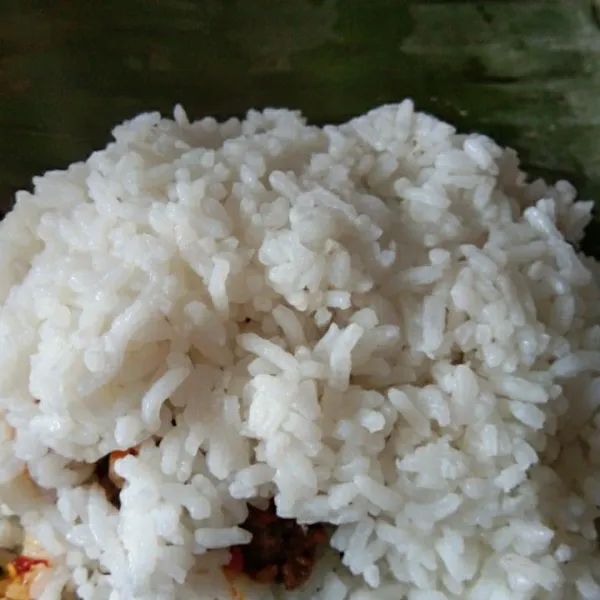 Tambahkan 1/2 porsi nasi lagi di atasnya, padatkan dan gulung , lipat kedalam di kedua sisinya.