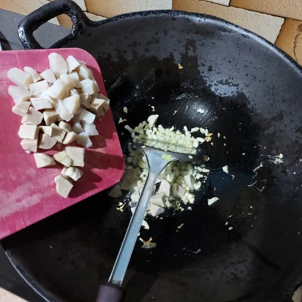 Panaskan minyak goreng di dalam wok, tumis bawang putih hingga berubah warna, masukkan bakso dan tumis sebentar.