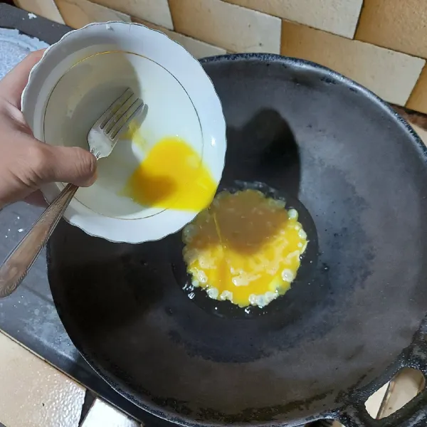 Pertama, kocok telur dan tambahkan sejumput garam, tuang telur ke dalam wok.