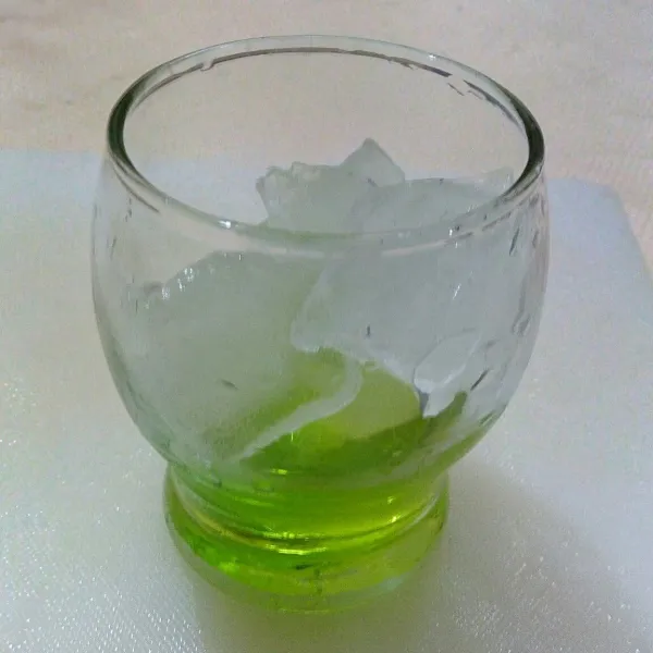 Siapkan gelas saji, masukkan es batu dan sirup melon.