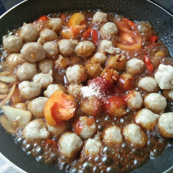 Masukkan bakso, kemudian tambahkan air, garam, kecap manis, saus tomat, dan kaldu jamur. Masak hingga bumbu menyerap.