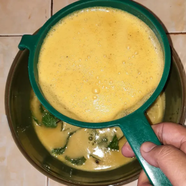 Tuang jus markisa (sambil di saring) ke dalam wadah yang berisi buah markisa dan daun mint.