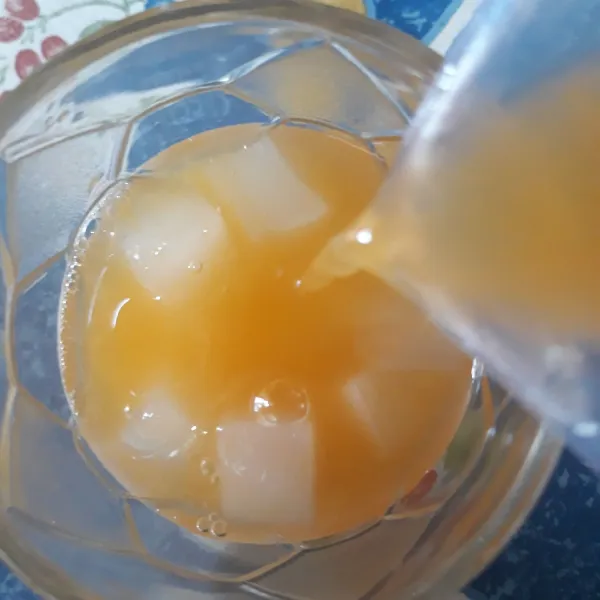 Masukkan air jeruk kedalam gelas berisi nata decoco.