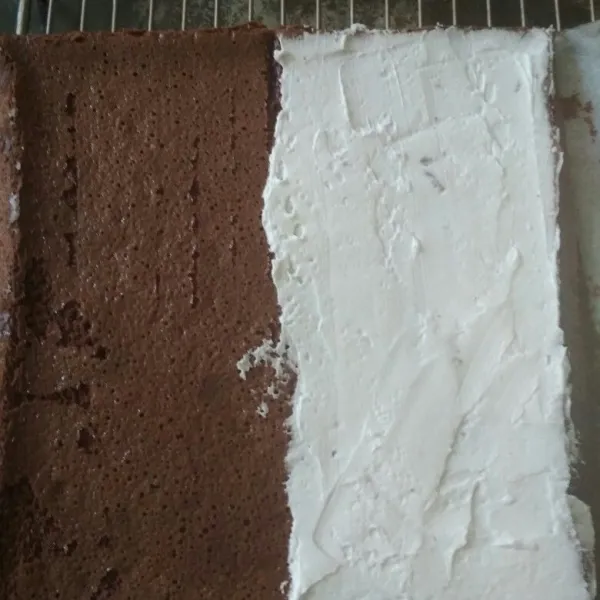 Setelah matang keluarkan loyang dan hentakan 2-3 kali agar cake tidak turun, lalu potong menjadi dua bagian dan dinginkan, setelah dingin poles dengan buttercream tumpuk cake dan simpan dalam kulkas sebentar.