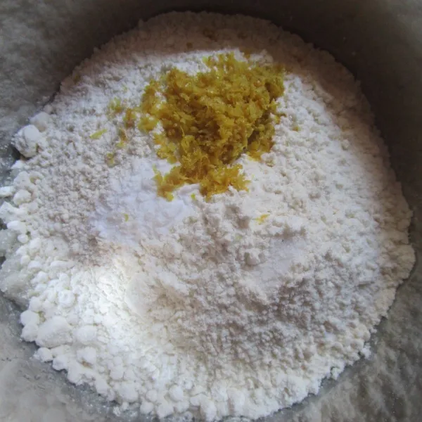 Masukkan minyak dan gula pasir dalam wadah. Aduk rata dengan whisk. Tambahkan tepung, parutan kulit lemon dan baking soda. Aduk rata dengan whisk.
