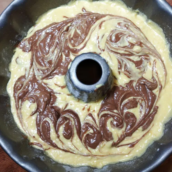 Oles loyang tulban 24 cm dengan butter tipis saja dan taburi terigu secukupnya. Tuang 1/2 adonan putih ke atas loyang. Tata 1/2 adonan cokelat di atasnya. Tuang lagi sisa adonan putih di atasnya. Terakhir Tuang sisa adonan cokelat di bagian paling atas, buat motif marmer menggunakan garpu atau sumpit.