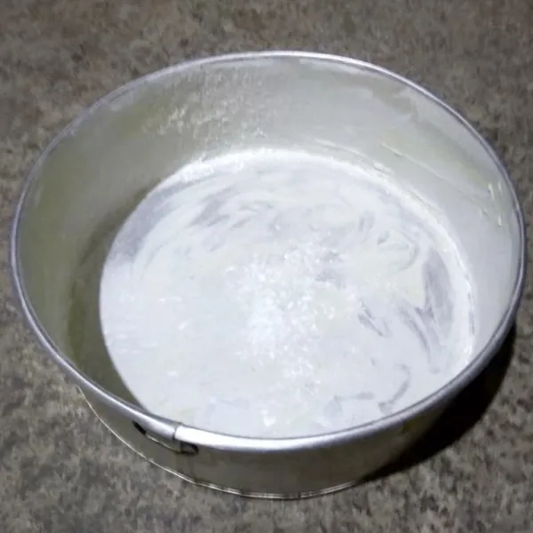 Olesi loyang dengan mentega dan taburi terigu.