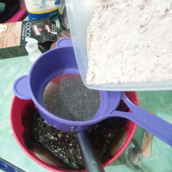 Masukkan adonan tepung sambil diayak kedalan adonan coklat lalu aduk hingga semua tercampur rata.