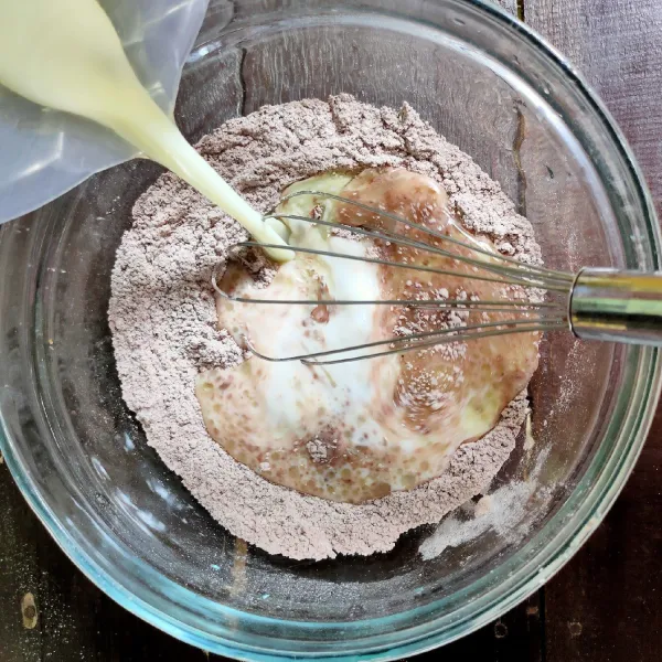 Tuangkan susu dan minyak kedalam campuran tepung kering.