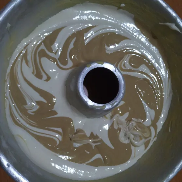 Tuang sebagian adonan putih ke dalam loyang, lalu sebagian adonan coklat, lalu adonan putih lagi, terakhir adonan coklat, lalu buat motif dengan menggunakan sumpit.