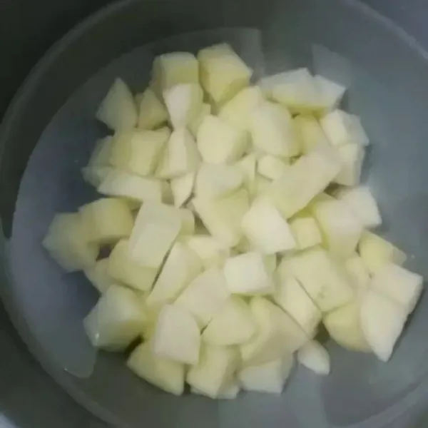 Kupas kentang potong dadu lalu rendam dengan air.