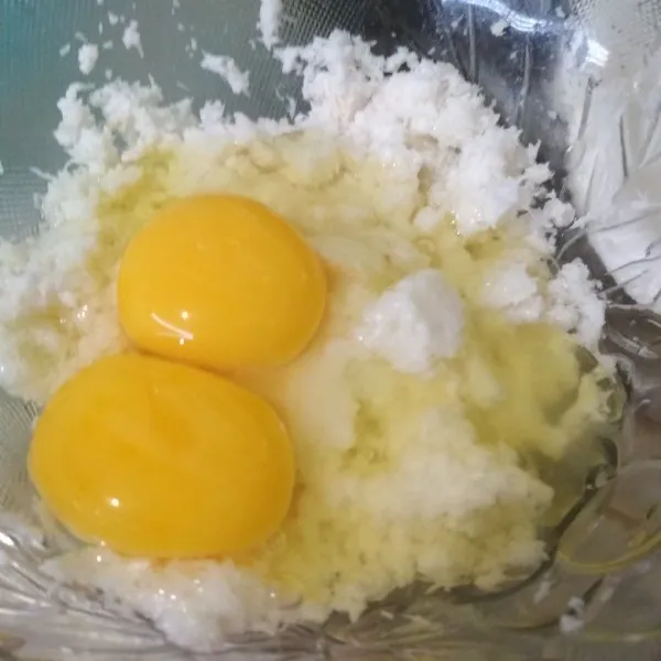 Tambahkan garam, kaldu jamur, dan telur ke dalam mangkok berisi kelapa, kocok hingga tercampur rata.