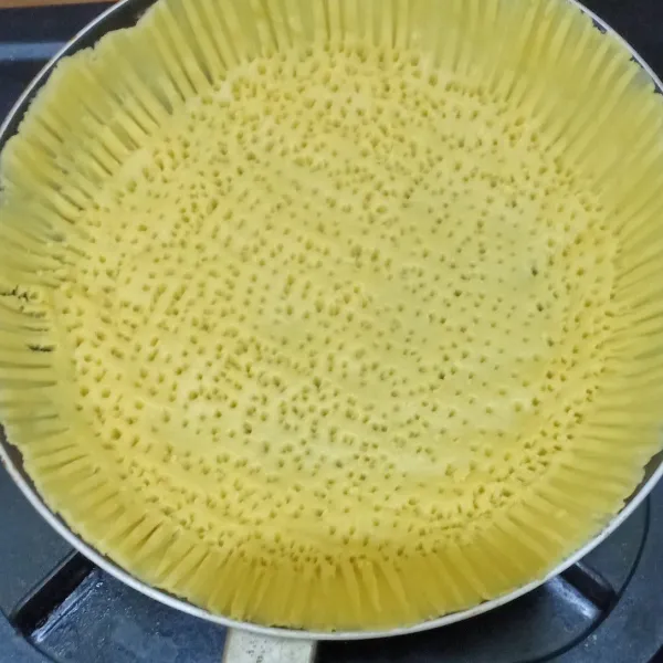 Tusuk-tusuk adonan di teflon dengan garpu.
