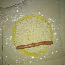 Siapkan plastik dan letakkan telur dadar diatasnya. Beri adonan tahu secara merata dan tambahkan sosis.