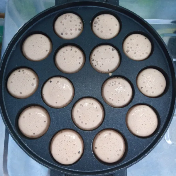 Panaskan cetakan takoyaki. Tuang secukupnya adonan. Biarkan sampai bergelembung. Kemudian beri taburan gula pasir.