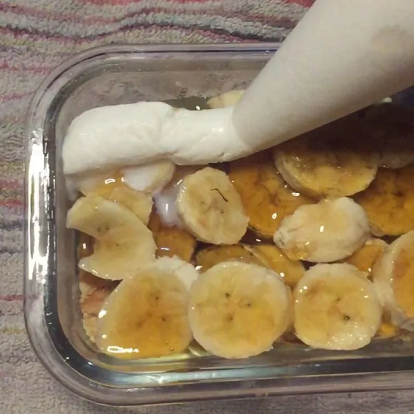 Tuang whipping cream di atas layer pisang caramel hingga membentuk layer terakhir.