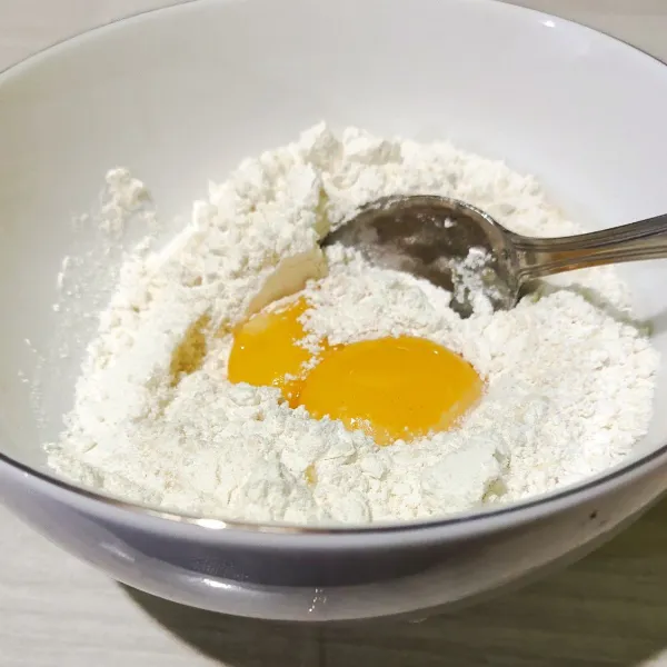 Tambahkan kuning telur. Aduk rata. Tambahkan mentega cair. Aduk rata. Sementara itu, kocok putih telur bersama gula pasir hingga pucat dan kaku.