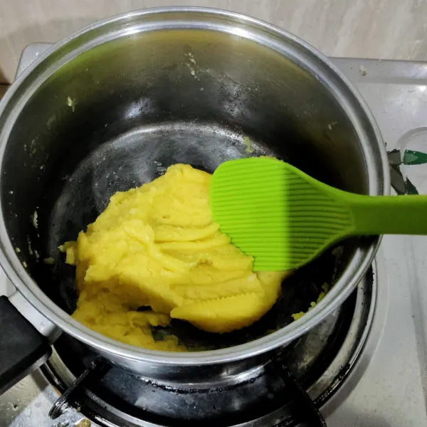 Kecilkan api hingga hampur mati, masukkan tepung terigu, aduk cepat hingga kalis. Matikan api. Biarkan dingin.