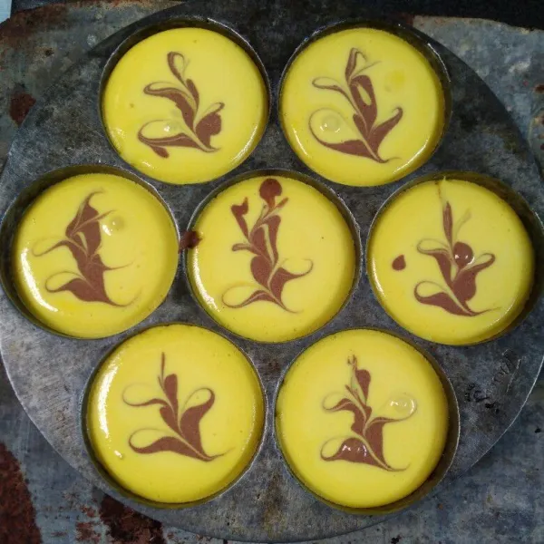 Panaskan cetakan (cetakan kue lumpur, alasi dengan tutup kaleng bekas atau sejenisnya). Tuang adonan kuning, tambahkan sedikit adonan coklat, hias sesuai selera.