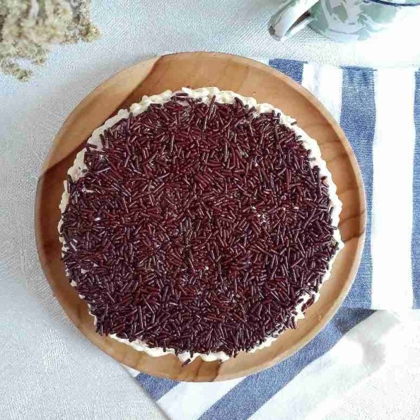 Setelah matang, keluarkan cake dari loyangnya. Hias dengan olesan buttercream di atas cakenya dan taburi dengan mesis. Sajikan.