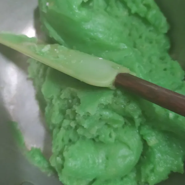 Tambahkan pasta pandan, kecilkan api, masukkan tepung terigu. Aduk cepat hingga rata sampai adonan kalis, angkat.