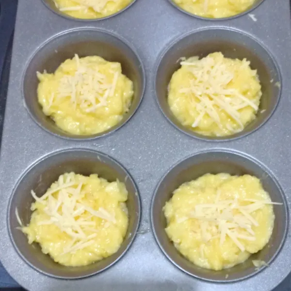 Tuang dalam cetakan muffin, beri taburan keju parut di atasnya.