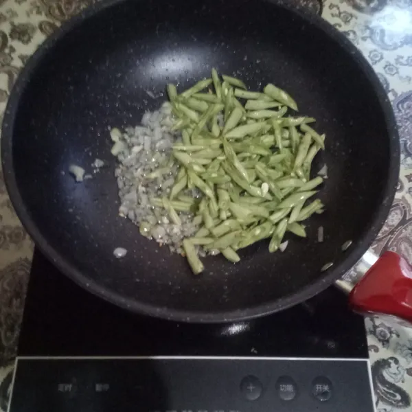 Panaskan minyak, tumis bawang putih dan bawang bombay hingga harum, masukkan buncis. Aduk rata.