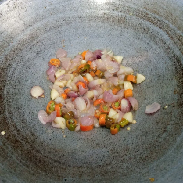 Tumis bawang merah dan bawang putih sampai harum dan layu. Masukkan cabai rawit. Aduk rata. Buang minyaknya.