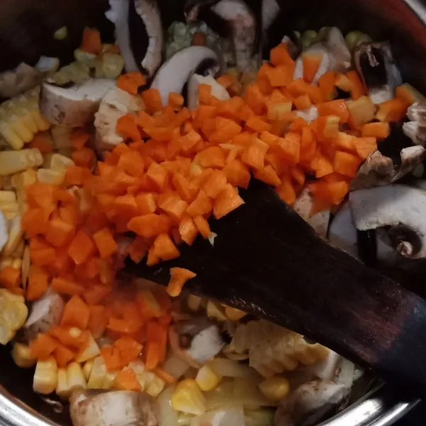 Tambahkan jagung, wortel yang sudah dipotong dadu kecil dan jamur,  aduk rata tumis hingga layu.