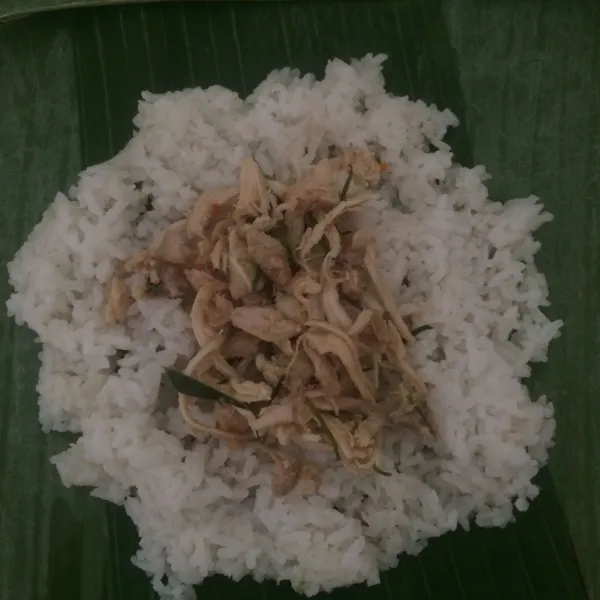 Siapkan daun pisang lalu tambahkan nasi dan beri isian suwir ayam. Bungkus