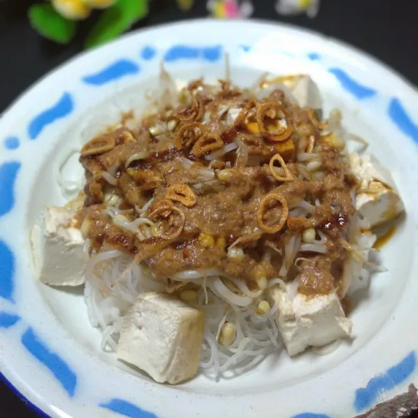 Tata di atas piring saji, lontong, bihun tahu dan taoge. Siram bumbu kacang, taburi bawang merah.