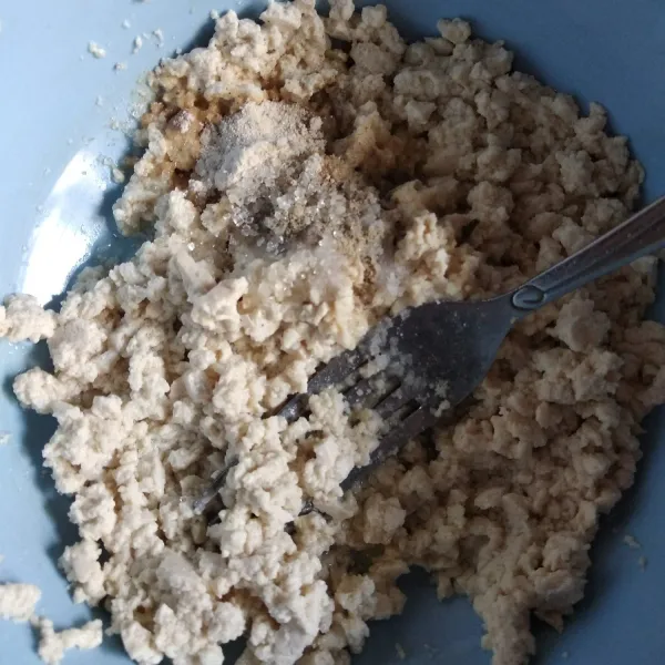 Haluskan tahu selagi panas dengan menggunakan garpu. Tambahkan kaldu jamur, bawang putih bubuk, gula, garam dan merica bubuk. Aduk rata.