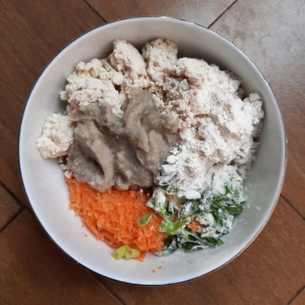 Siapkan wadah. Masukkan tahu, wortel parut, irisan daun bawang, bumbu halus dan tepung terigu. Aduk rata.