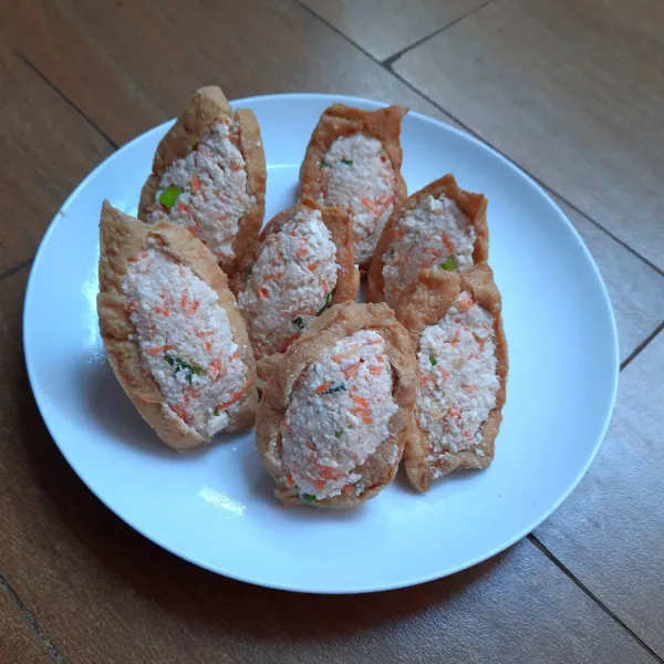 Ambil 1 buah tahu kulit. Sobek bagian atasnya. Kerok bagian putihnya (jika ada) dengan sendok. Beri isian adonan tahu. Lakukan hingga adonan dan tahu kulit habis.