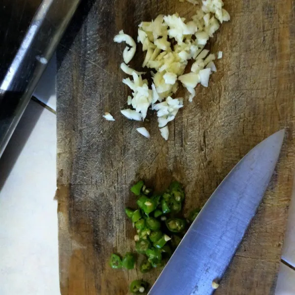 Iris tipis-tipis bawang putih dan cabe rawit hijau.