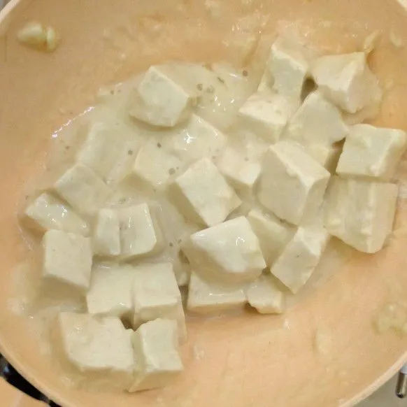 Potong kotak-kotak tahu. Lumuri dengan tepung beras, bawang putih bubuk, ketumbar bubuk,. sedikit air, garam, lada dan kaldu jamur. Campur hingga rata.