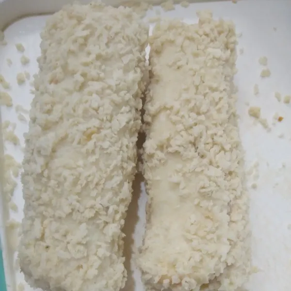 Celupkan gulungan roti ke dalam bahan pencelup kemudian gulingkan di atas tepung roti.