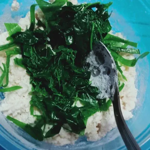 Tambahkan daun kelor dan daun bawang ke dalam adonan tahu, lalu aduk rata.
