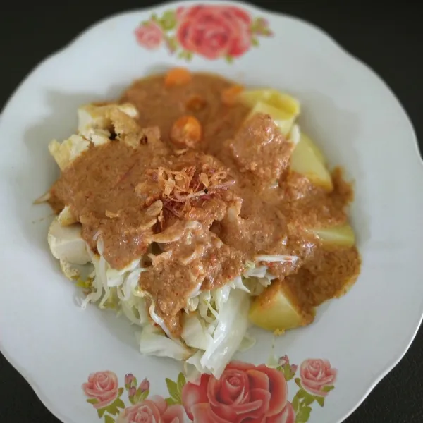Siapkan piring saji, potong-potong kentang dan wortel. Tambahkan tahu goreng, kol, tauge. Tuang bumbu gado-gado di atasnya. Tambahkan bawang goreng, aduk rata.