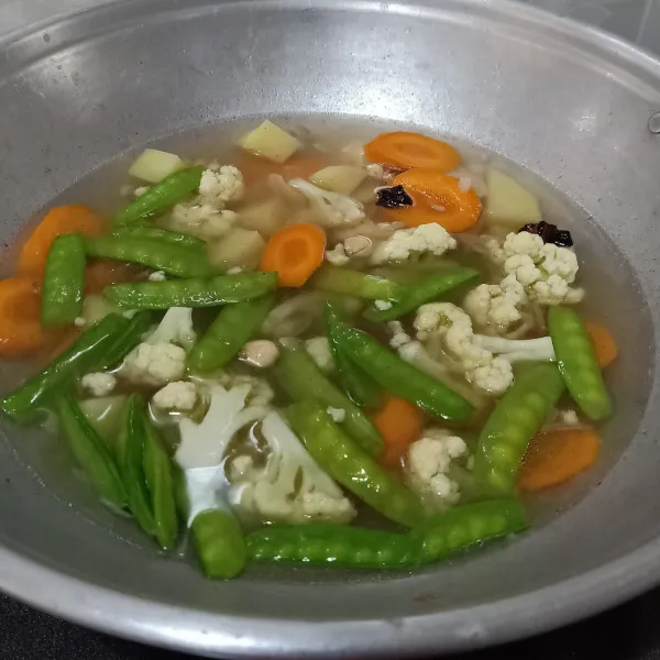 Setelah mendidih, masukkan wortel dan kentang, masak beberapa saat. Kemudian masukkan bunga kol dan kapri. Bumbui merica bubuk dan kaldu jamur/bubuk. Masak sampai sayuran empuk tapi masih renyah (jangan terlalu lunak).