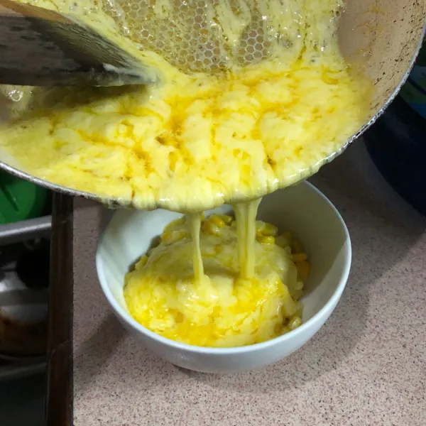 Letakkan jagung di wadah lalu tuang campuran margarin, butter dan mozzarella selagi panas.