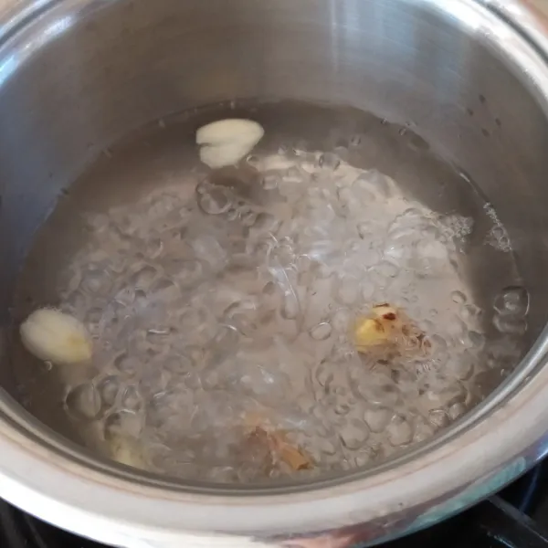 Masukan bawang putih dan kunci ke dalam panci berisi air. Lalu didihkan hingga keluar aromanya.