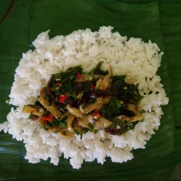 Ambil daun pisang, letakkan nasi secukupnya dan tumisan jamur, kemudian gulung dan sematkan lidi di samping-sampingnya.