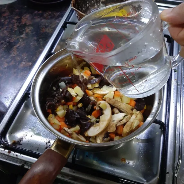 Tambahkan air lalu tutup dan biarkan mendidih. Cek kematangan kentang dan wortel.
