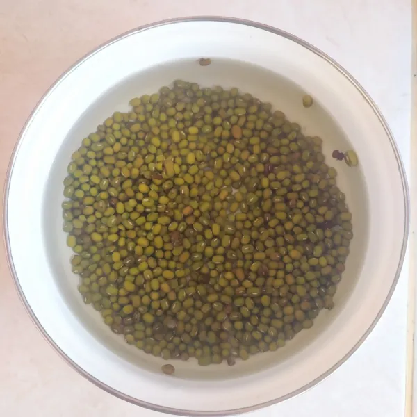 Rendam biji kacang hijau dengan air panas selama 3-4 jam. Proses ini perlu supaya nantinya gak perlu waktu lama buat merebus, karena kacang hijau sudah empuk.