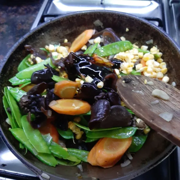 Setelah wortel mulai empuk dan tidak langu, masukkan kapri, tumis hingga agak layu. Masukkan jamur kuping dan jagung, aduk-aduk. Masukkan saus tiram, garam, kaldu jamur.