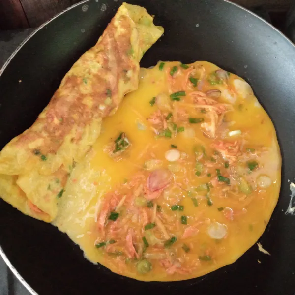 Taruh telur yang sudah digulung di pinggir tuangkan adonan telur dadar lagi di tengah teflon.